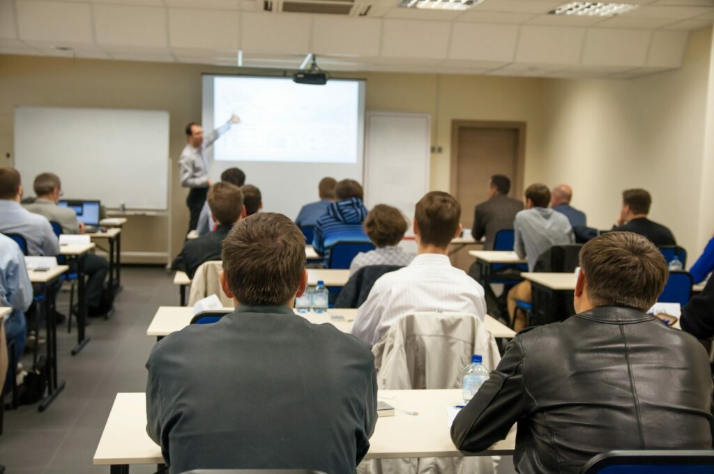 Rear view of people sitting in a class listening to a training presentation
